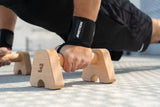 Nahaufnahme: Push-Up auf Bmotion Parallettes Small mit Fokus auf Handgelenksposition, Grip und Wrist Wraps – funktionelles Outdoor-Training mit Holz-Equipment.