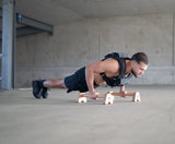 Athlet mit Bmotion Gewichtsweste macht Liegestütze auf Holz-Parallettes im urbanen Trainingsspot.