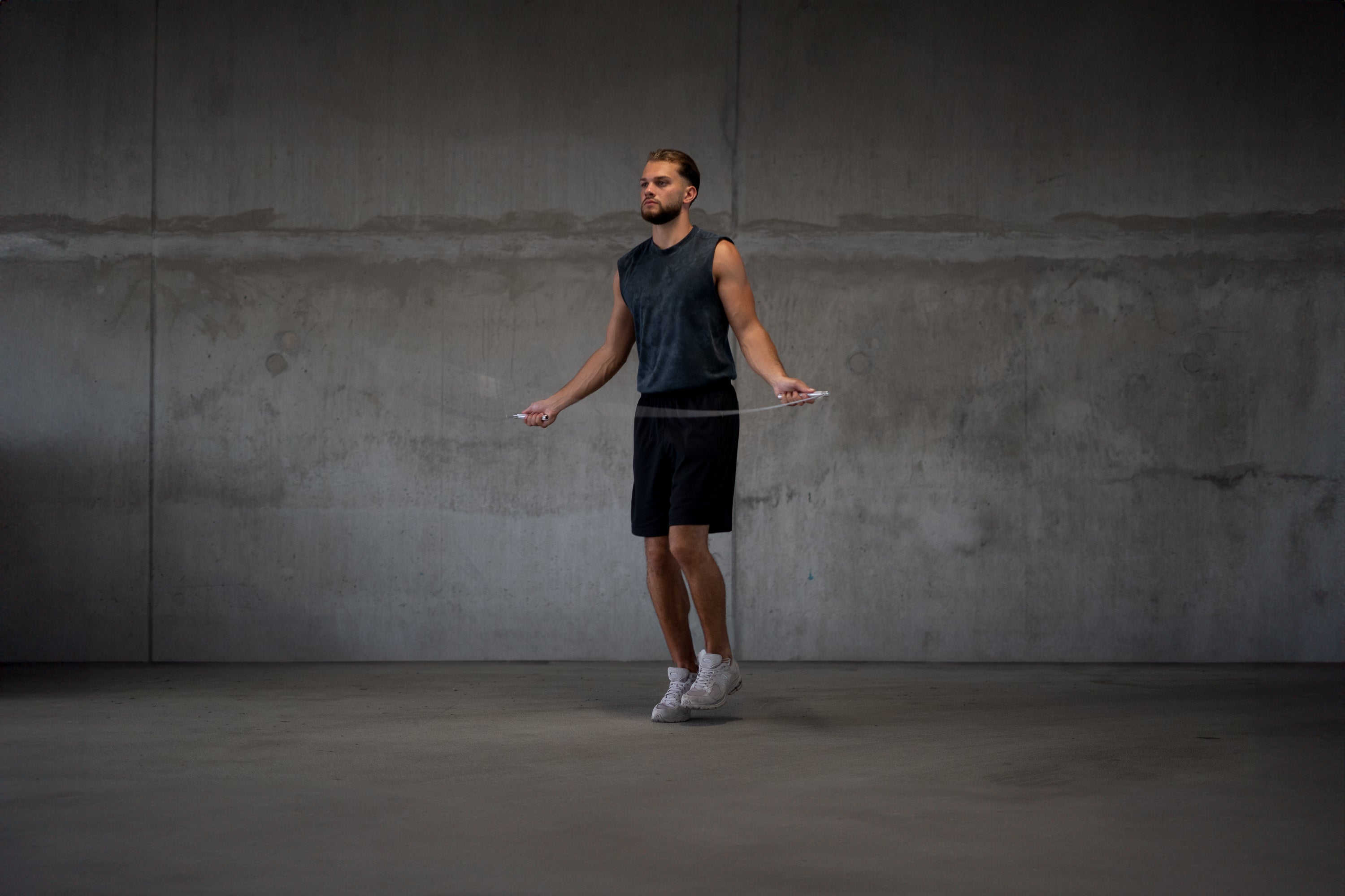 Athlet beim Seilspringen mit dem Bmotion Speedrope vor Betonwand – Ganzkörpertraining für Ausdauer, Koordination und Rhythmus im Indoorbereich.
